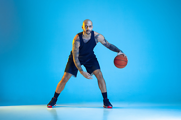 Image showing Young basketball player training isolated on blue studio background in neon light