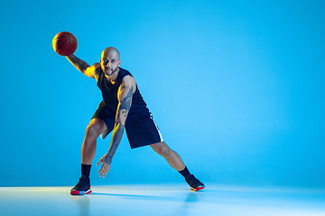 Image showing Young basketball player training isolated on blue studio background in neon light