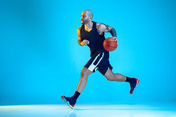 Image showing Young basketball player training isolated on blue studio background in neon light