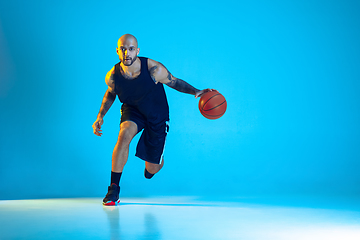 Image showing Young basketball player training isolated on blue studio background in neon light