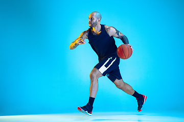 Image showing Young basketball player training isolated on blue studio background in neon light