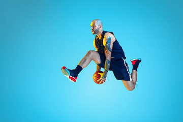 Image showing Young basketball player training isolated on blue studio background in neon light