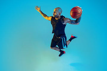 Image showing Young basketball player training isolated on blue studio background in neon light