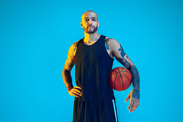 Image showing Young basketball player training isolated on blue studio background in neon light