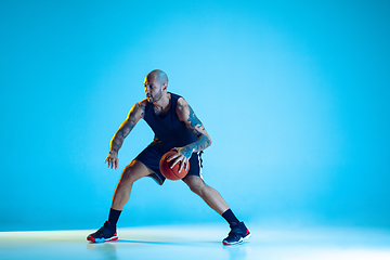 Image showing Young basketball player training isolated on blue studio background in neon light