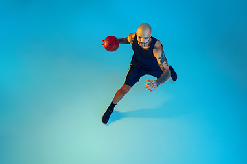 Image showing Young basketball player training isolated on blue studio background in neon light