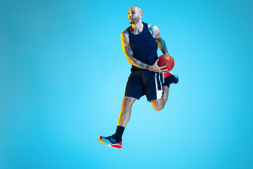 Image showing Young basketball player training isolated on blue studio background in neon light