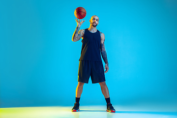 Image showing Young basketball player training isolated on blue studio background in neon light