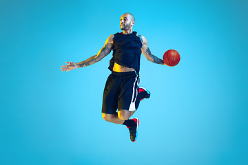 Image showing Young basketball player training isolated on blue studio background in neon light