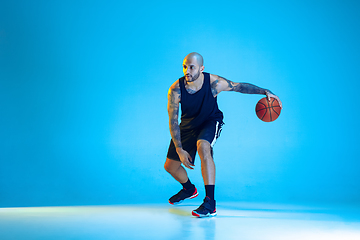 Image showing Young basketball player training isolated on blue studio background in neon light