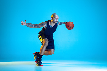 Image showing Young basketball player training isolated on blue studio background in neon light