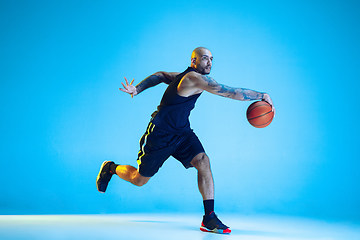 Image showing Young basketball player training isolated on blue studio background in neon light