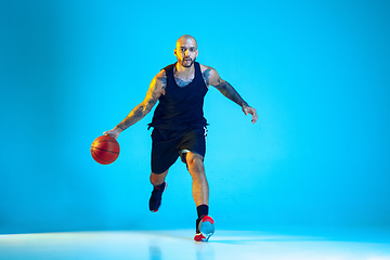 Image showing Young basketball player training isolated on blue studio background in neon light