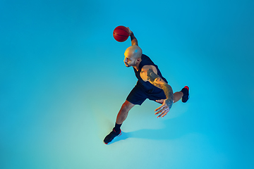 Image showing Young basketball player training isolated on blue studio background in neon light