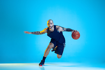 Image showing Young basketball player training isolated on blue studio background in neon light