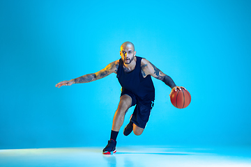 Image showing Young basketball player training isolated on blue studio background in neon light