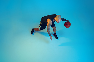 Image showing Young basketball player training isolated on blue studio background in neon light