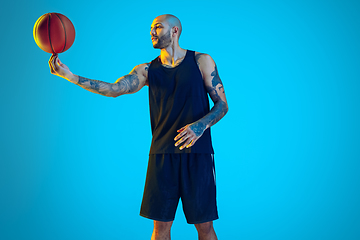 Image showing Young basketball player training isolated on blue studio background in neon light