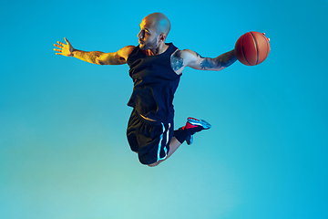 Image showing Young basketball player training isolated on blue studio background in neon light