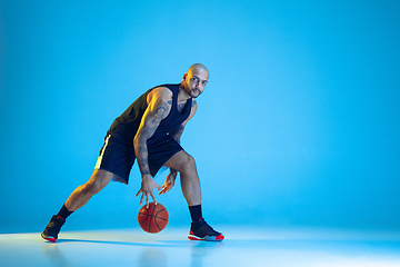 Image showing Young basketball player training isolated on blue studio background in neon light