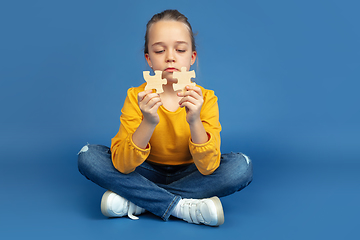 Image showing Portrait of sad little girl sitting on blue studio background, autism concept