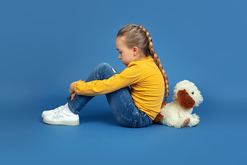 Image showing Portrait of sad little girl sitting on blue studio background, autism concept