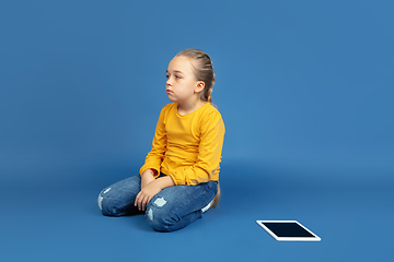 Image showing Portrait of sad little girl sitting on blue studio background, autism concept