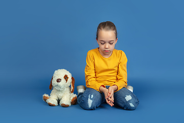 Image showing Portrait of sad little girl sitting on blue studio background, autism concept