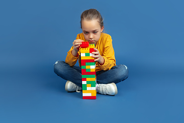 Image showing Portrait of sad little girl sitting on blue studio background, autism concept