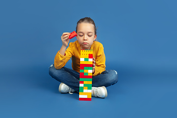 Image showing Portrait of sad little girl sitting on blue studio background, autism concept