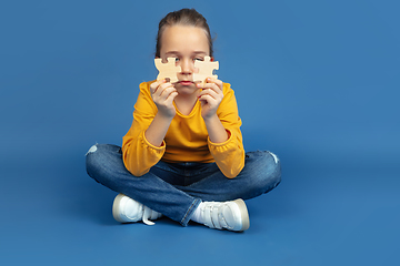 Image showing Portrait of sad little girl sitting on blue studio background, autism concept