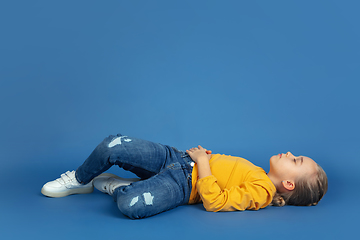 Image showing Portrait of sad little girl sitting on blue studio background, autism concept