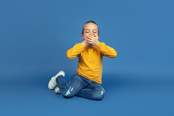 Image showing Portrait of sad little girl sitting on blue studio background, autism concept