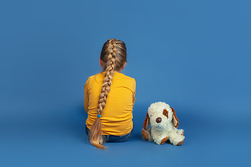 Image showing Portrait of sad little girl sitting on blue studio background, autism concept