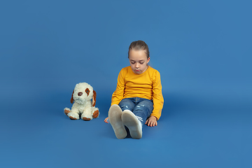 Image showing Portrait of sad little girl sitting on blue studio background, autism concept