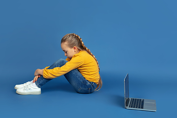 Image showing Portrait of sad little girl sitting on blue studio background, autism concept