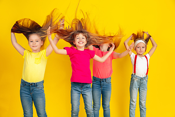 Image showing Happy children playing and having fun together on yellow studio background