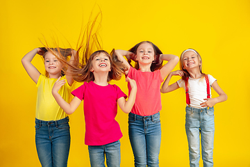 Image showing Happy children playing and having fun together on yellow studio background