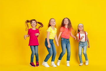 Image showing Happy children playing and having fun together on yellow studio background