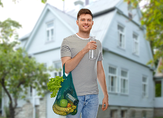 Image showing man with food in bag and water in glass bottle