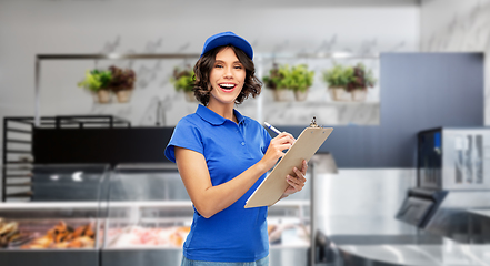 Image showing happy delivery girl with clipboard and pen writing