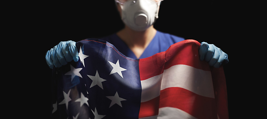 Image showing doctor in goggles and mask holding flag of america