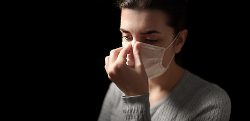 Image showing sick woman adjusting protective medical face mask