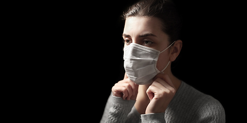 Image showing sick woman adjusting protective medical face mask