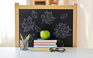 Image showing books, apple and school supplies on table at home