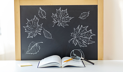 Image showing book with magnifier on table and chalkboard