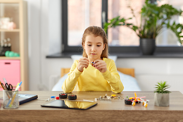 Image showing happy girl playing with robotics kit at home