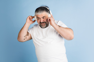 Image showing Handsome caucasian plus size male model isolated on blue studio background. Concept of inclusion, human emotions, facial expression