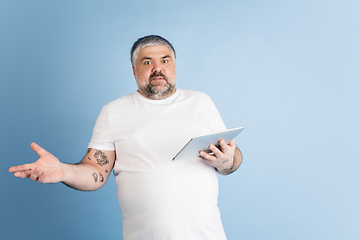 Image showing Handsome caucasian plus size male model isolated on blue studio background. Concept of inclusion, human emotions, facial expression