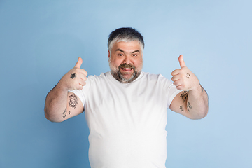 Image showing Handsome caucasian plus size male model isolated on blue studio background. Concept of inclusion, human emotions, facial expression